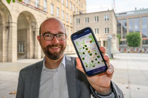 Stadtdirektor Sebastian Kopietz hält ein Smartphone mit der überarbeiteten Mängelmeder-App in Bochum in die Kamera.