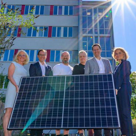 Oberbürgermeister Thomas Eiskirch und Mitarbeitende der Stadt Bochum halten eine Solar-Fläche, die durch Sonne Strom erzeugt.