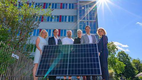 Oberbürgermeister Thomas Eiskirch und Mitarbeitende der Stadt Bochum halten eine Solar-Fläche, die durch Sonne Strom erzeugt.