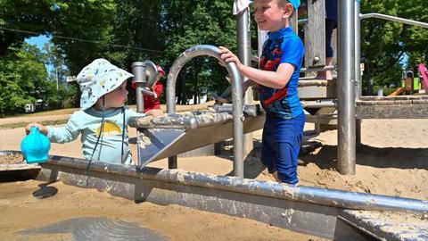 Kinder die auf einem Wasserspielplatz spielen.