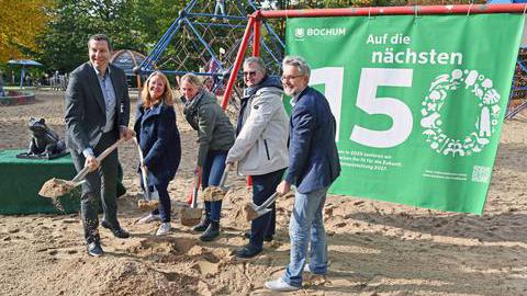 Fünf Personen stehen mit Schaufeln beim Spatenstich im Stadtpark vor einem grünen Banner.