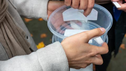 Zettel werden aus einer Plastikdose gezogen