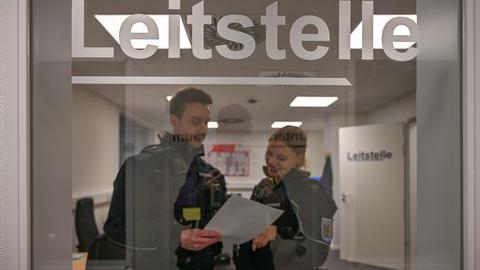 Zwei Mitarbeiter der Citywache stehen in Uniform hinter einer Glastür. 